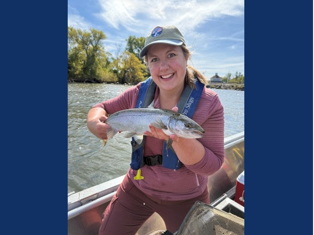 New York Sea Grant fisheries specialist Stacy Furgal holds a Lake Ontario Atlantic salmon from a boat