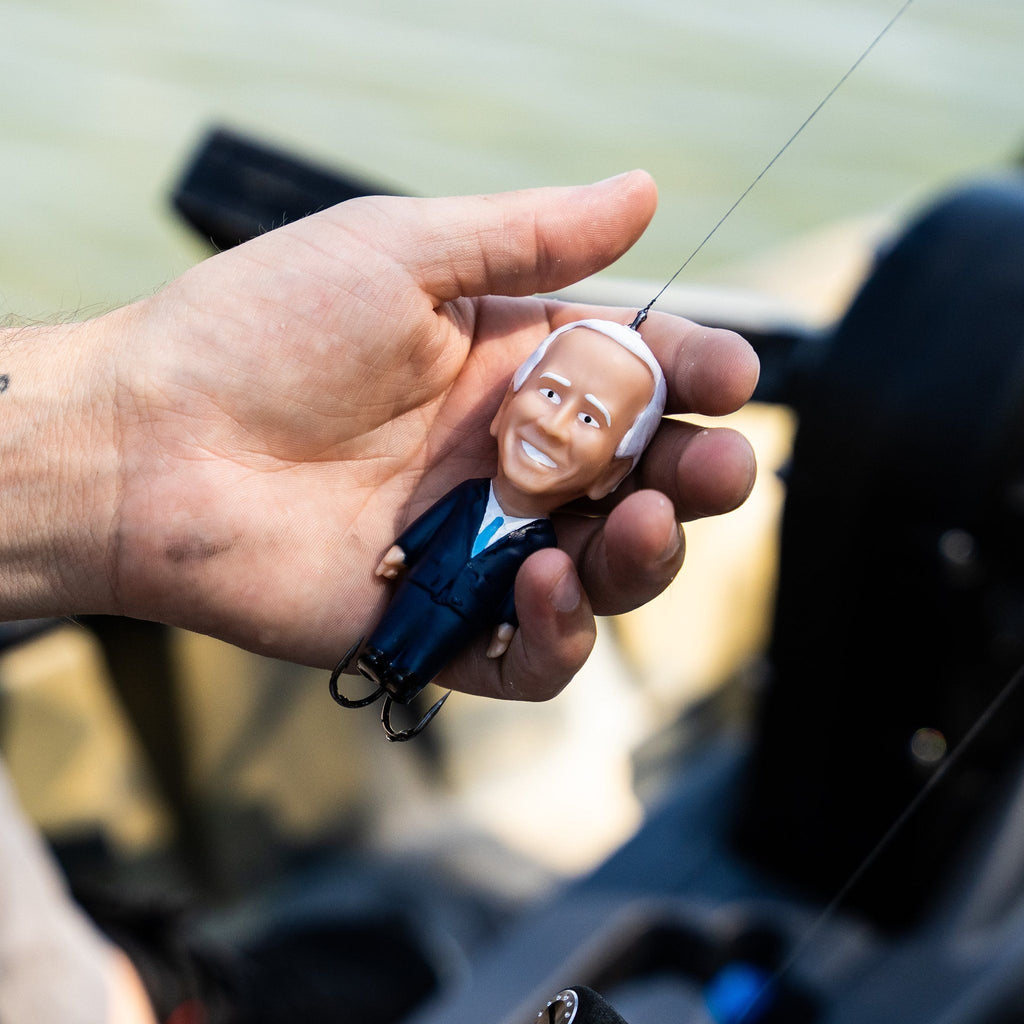 Hand holding a fishing lure with a face design, blurred background