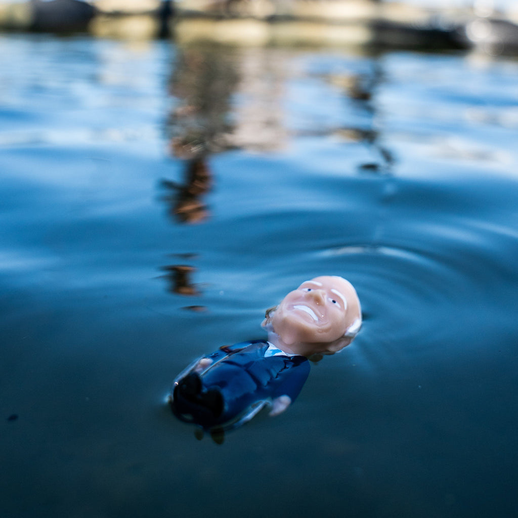 Toy figure of a person in a suit floating on water with a blurred background