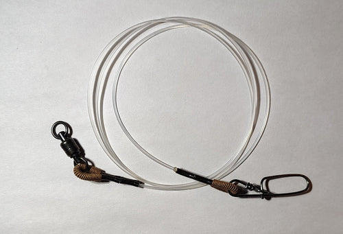 Fishing tackle including a spool of line and a package on a white surface