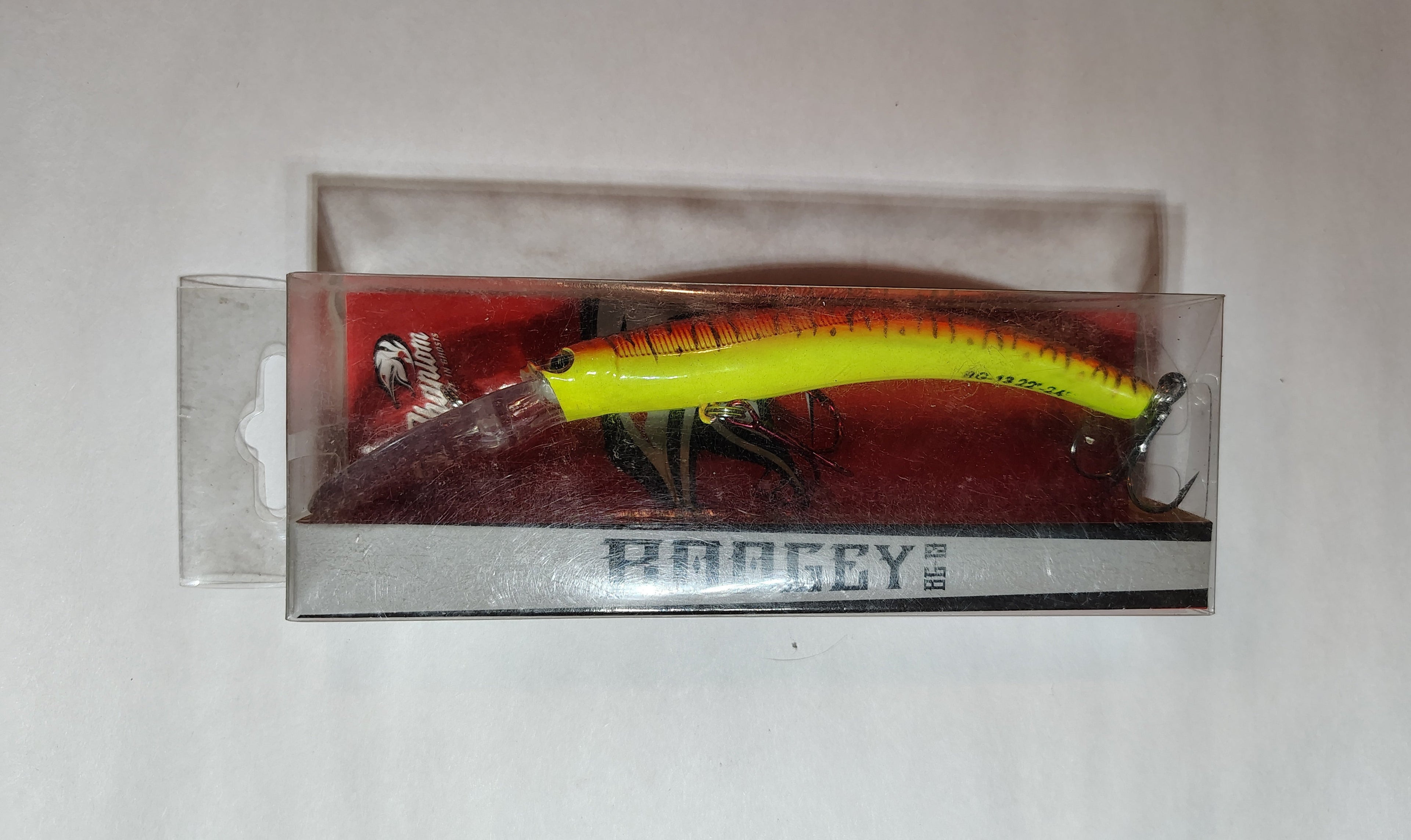 Yellow and black fishing lure in packaging on a white background