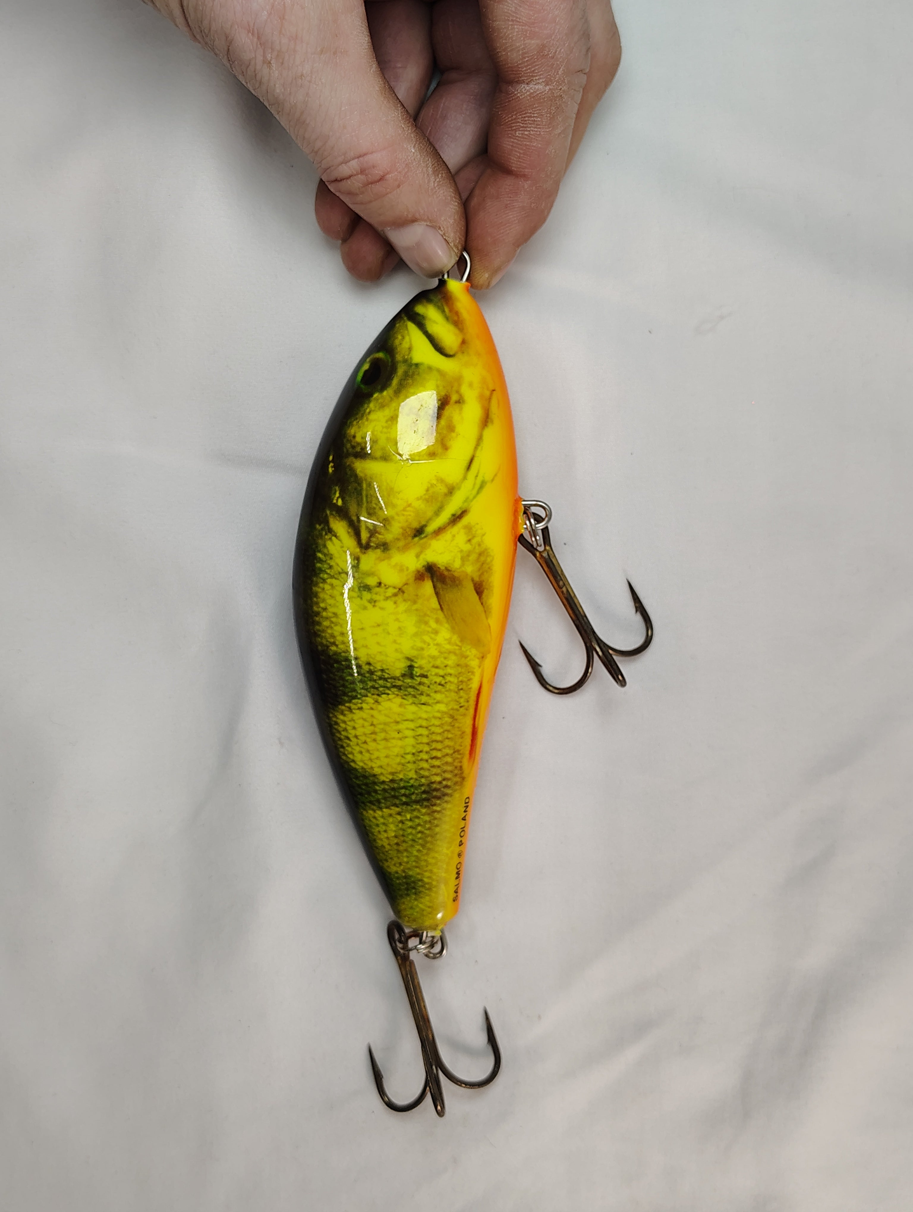 Fishing lure with a hand holding it on a light gray background