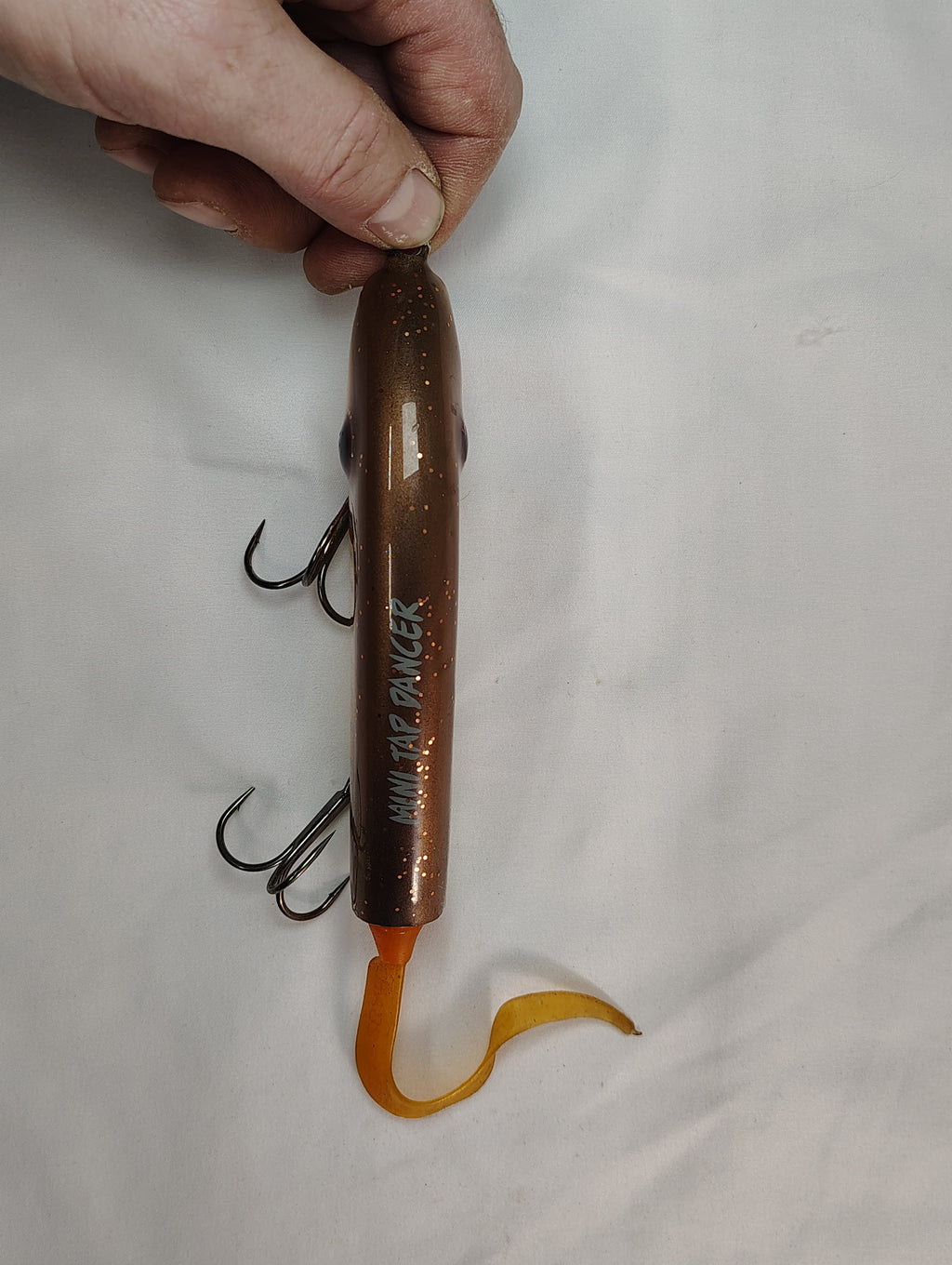 Lure with multiple hooks held by a hand on a white background