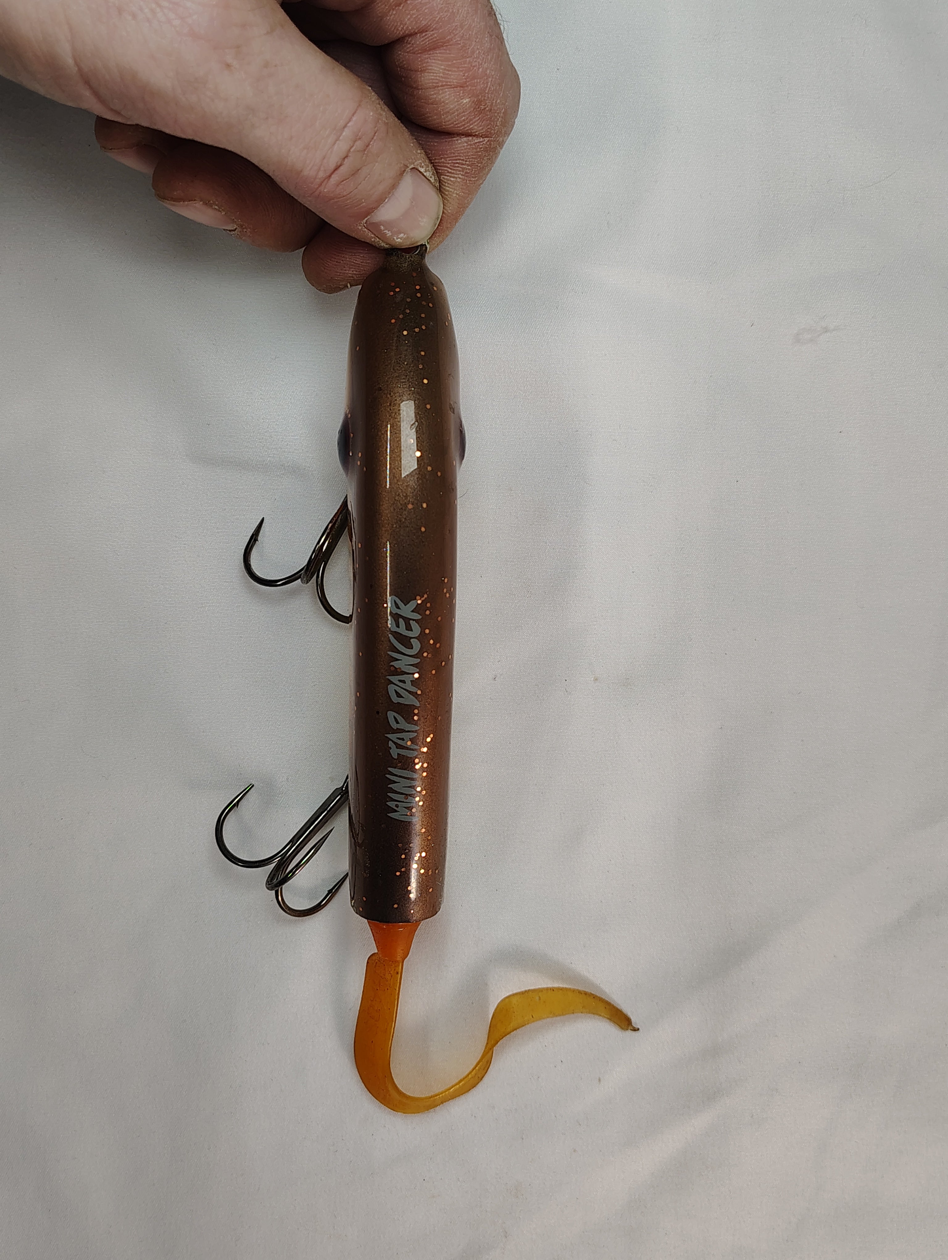 Lure with multiple hooks held by a hand on a white background