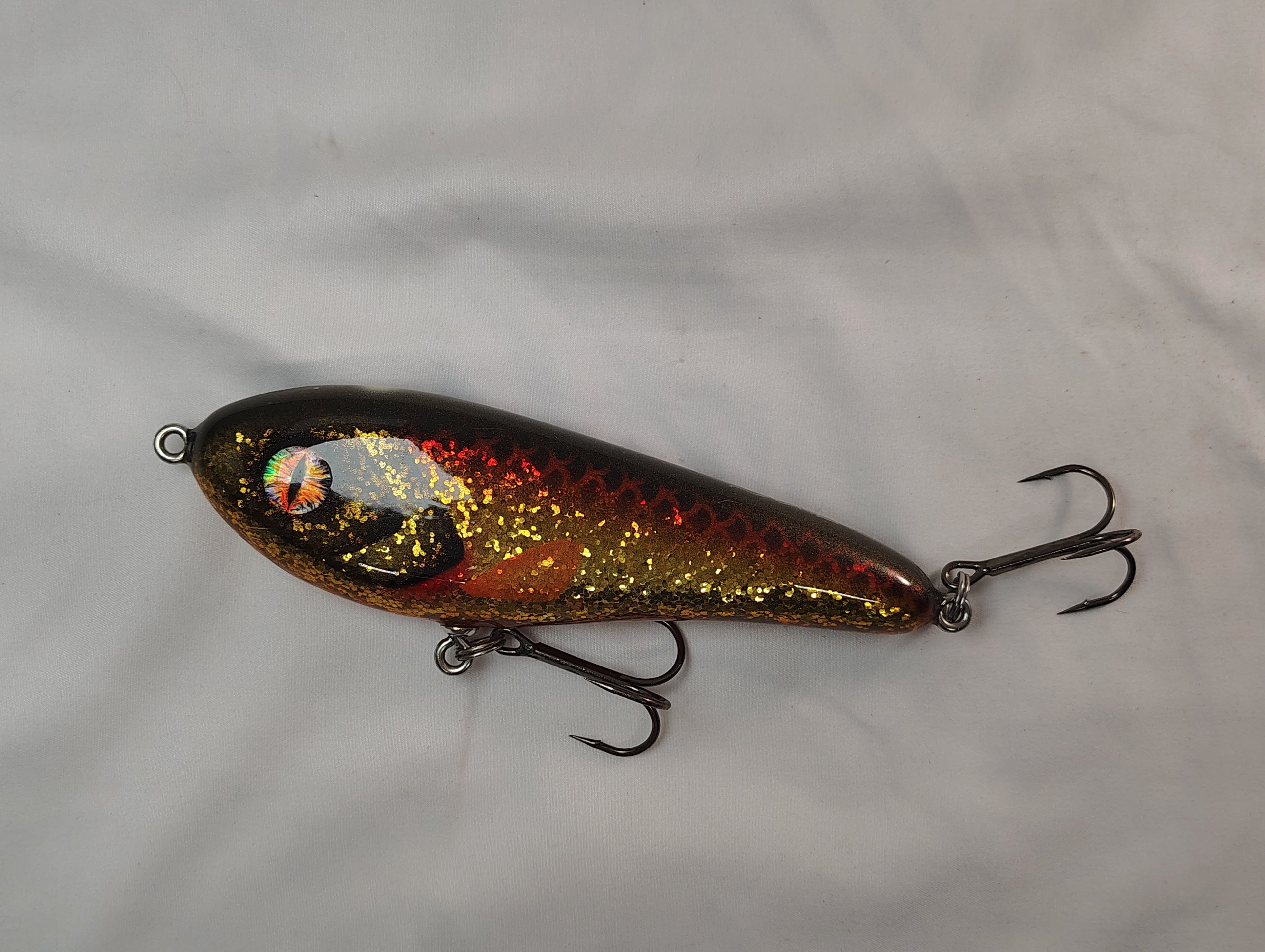 Fishing lure with metallic finish on a white background