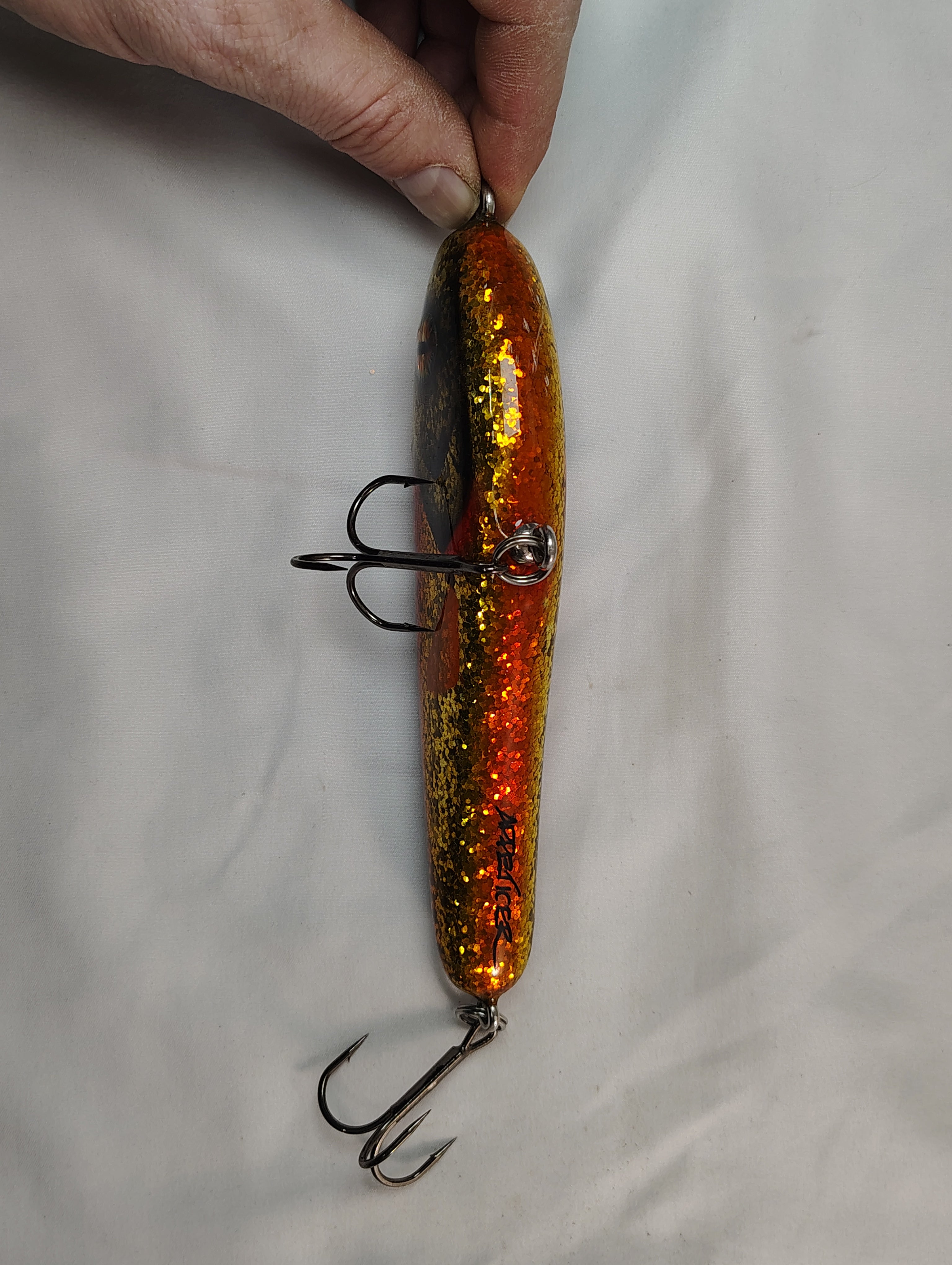 Fishing lure with orange and gold glitter on a white background