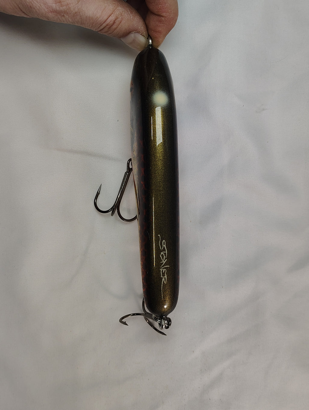 Fishing lure held by a hand on a white background