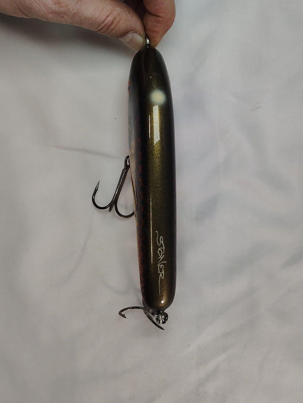 Fishing lure held by a hand on a white background