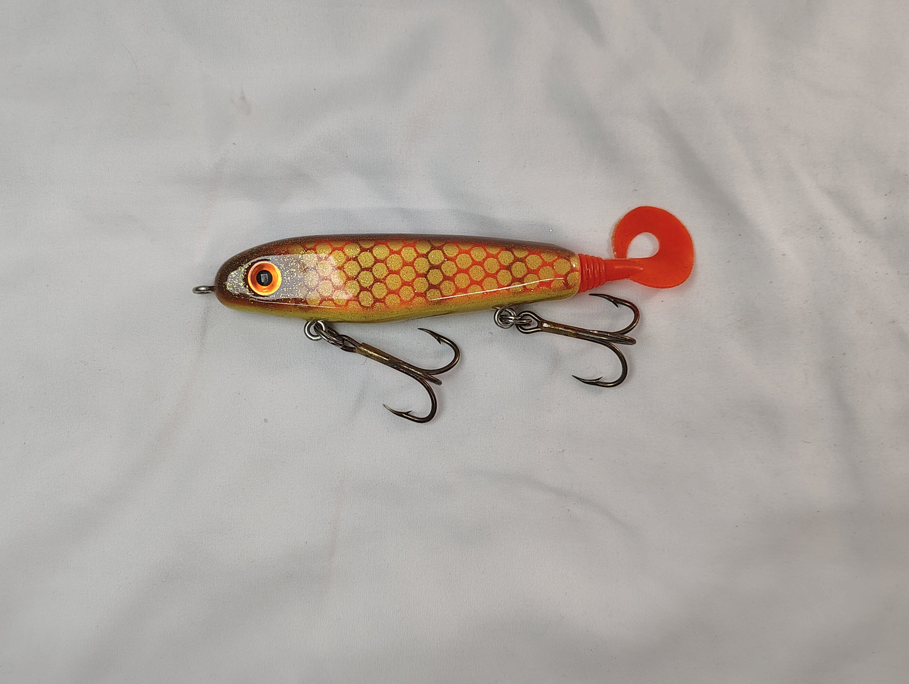 Fishing lure with a red and yellow pattern on a white background