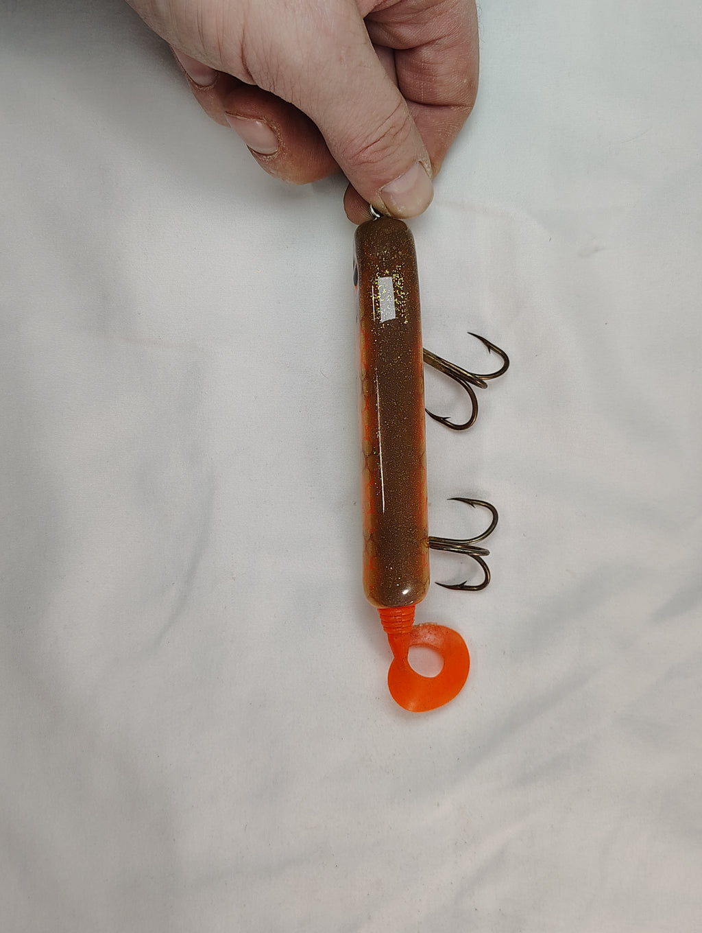 Hand holding a fishing lure with hooks on a white background