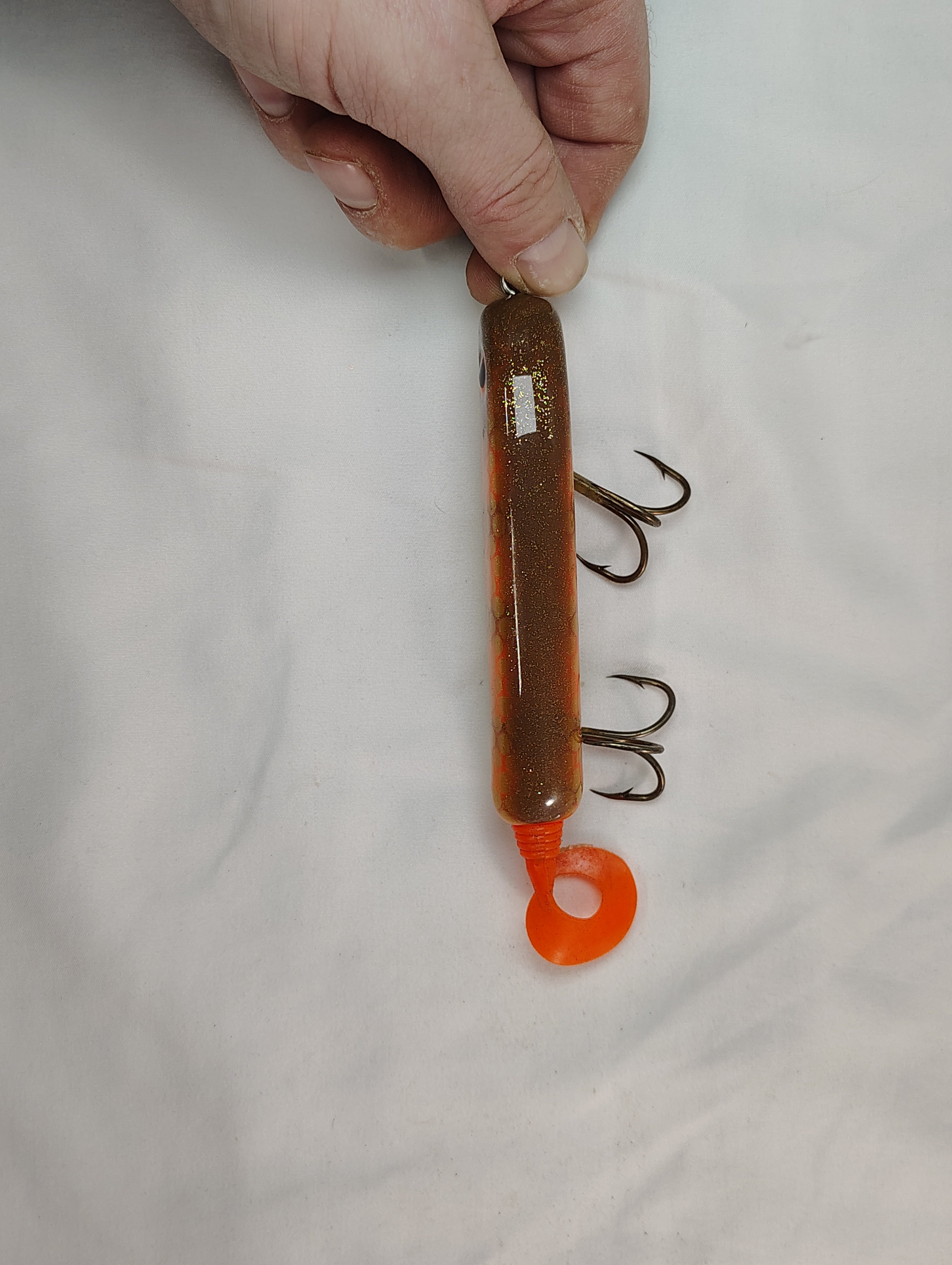 Hand holding a fishing lure with hooks on a white background