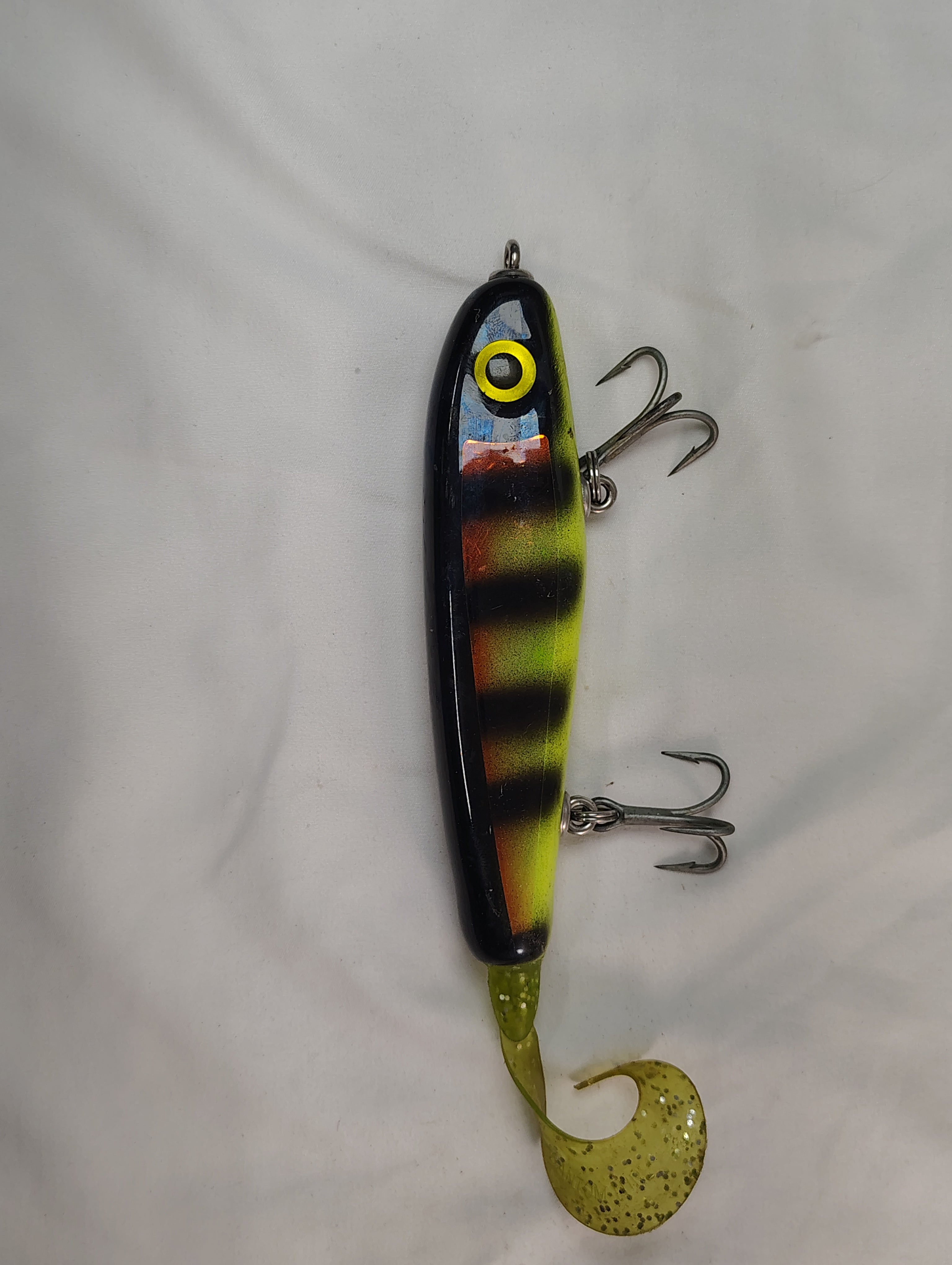 Colorful fishing lure with striped body and curly tail on a white background