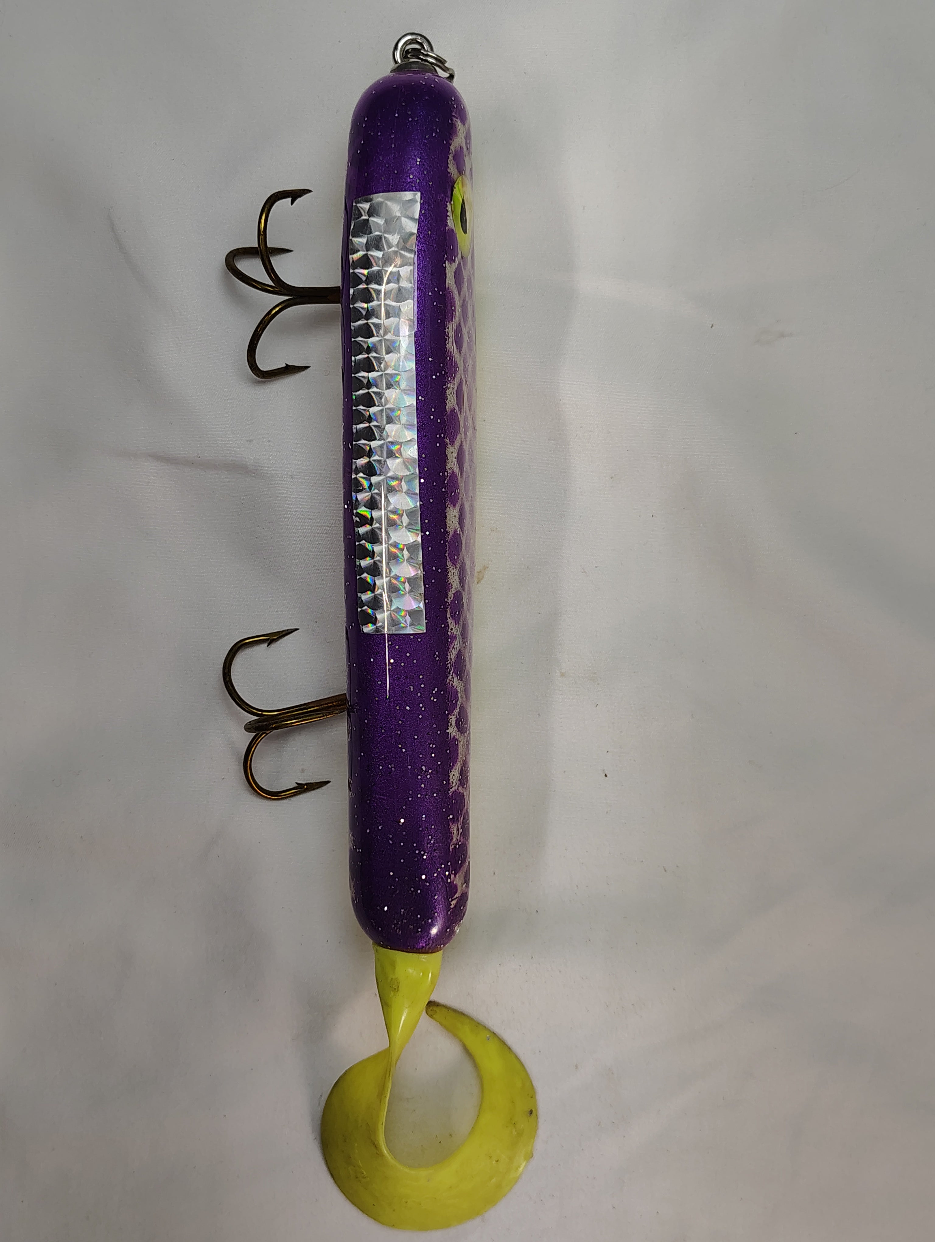 Purple and yellow fishing lure with multiple hooks on a white background