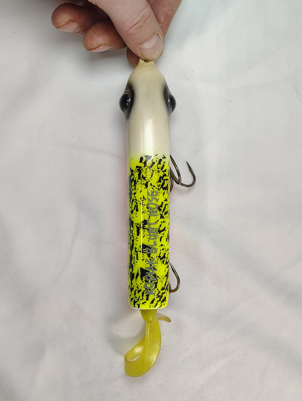 Fishing lure with a hand holding it against a white background