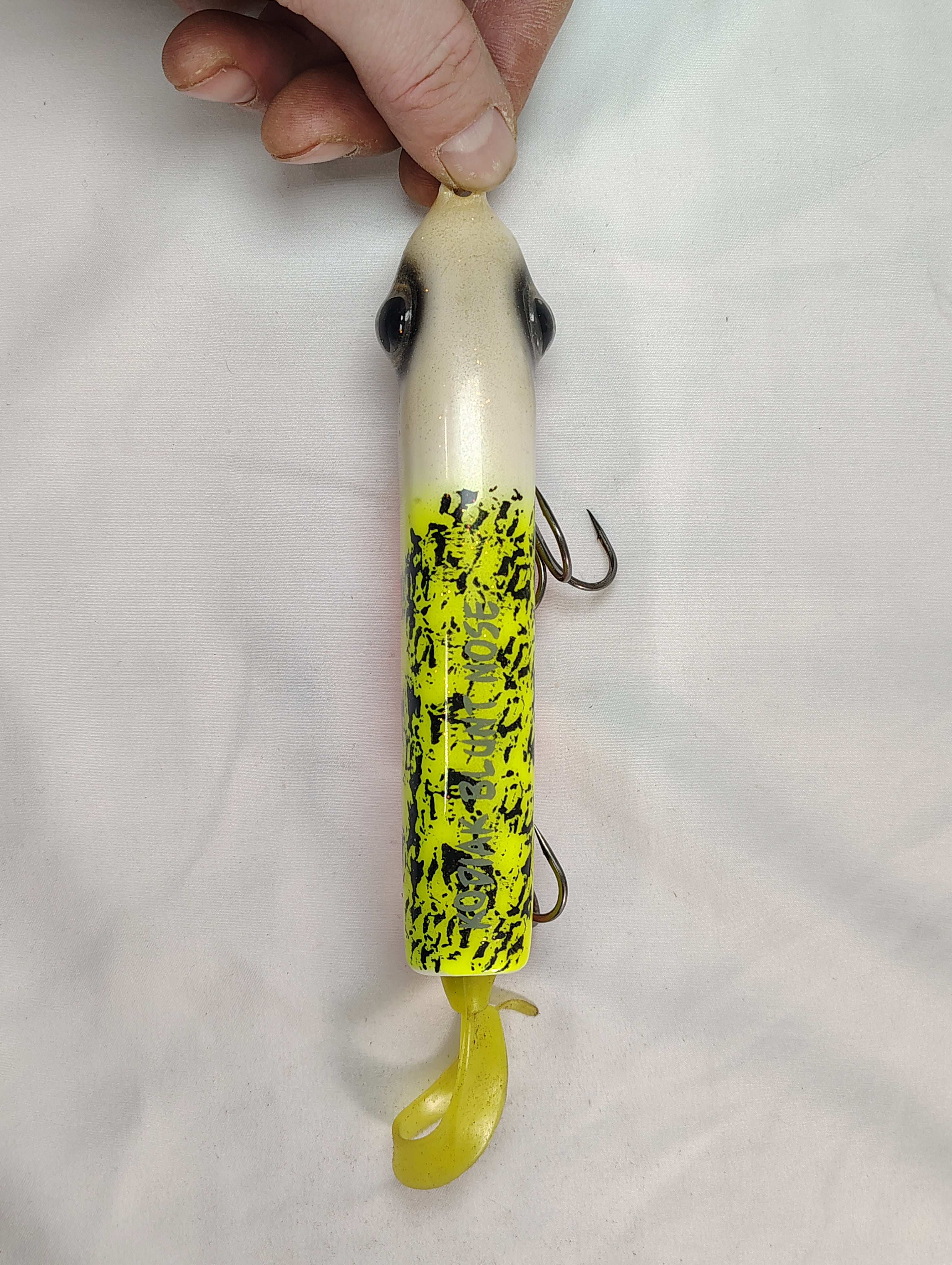 Fishing lure with a hand holding it against a white background
