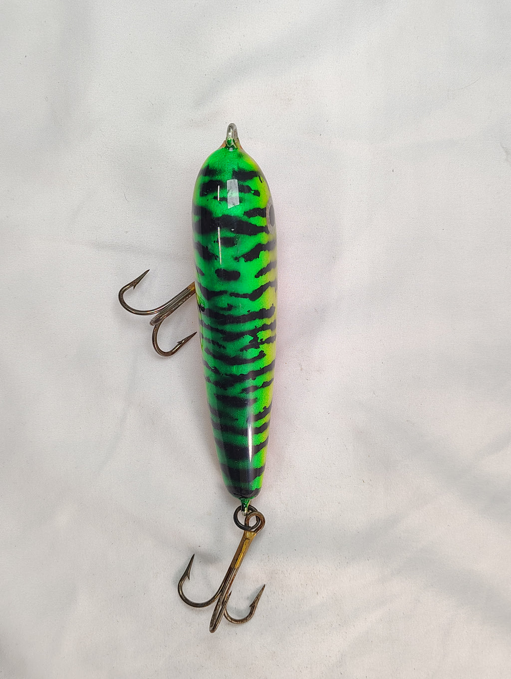 Green and black striped fishing lure on a white background