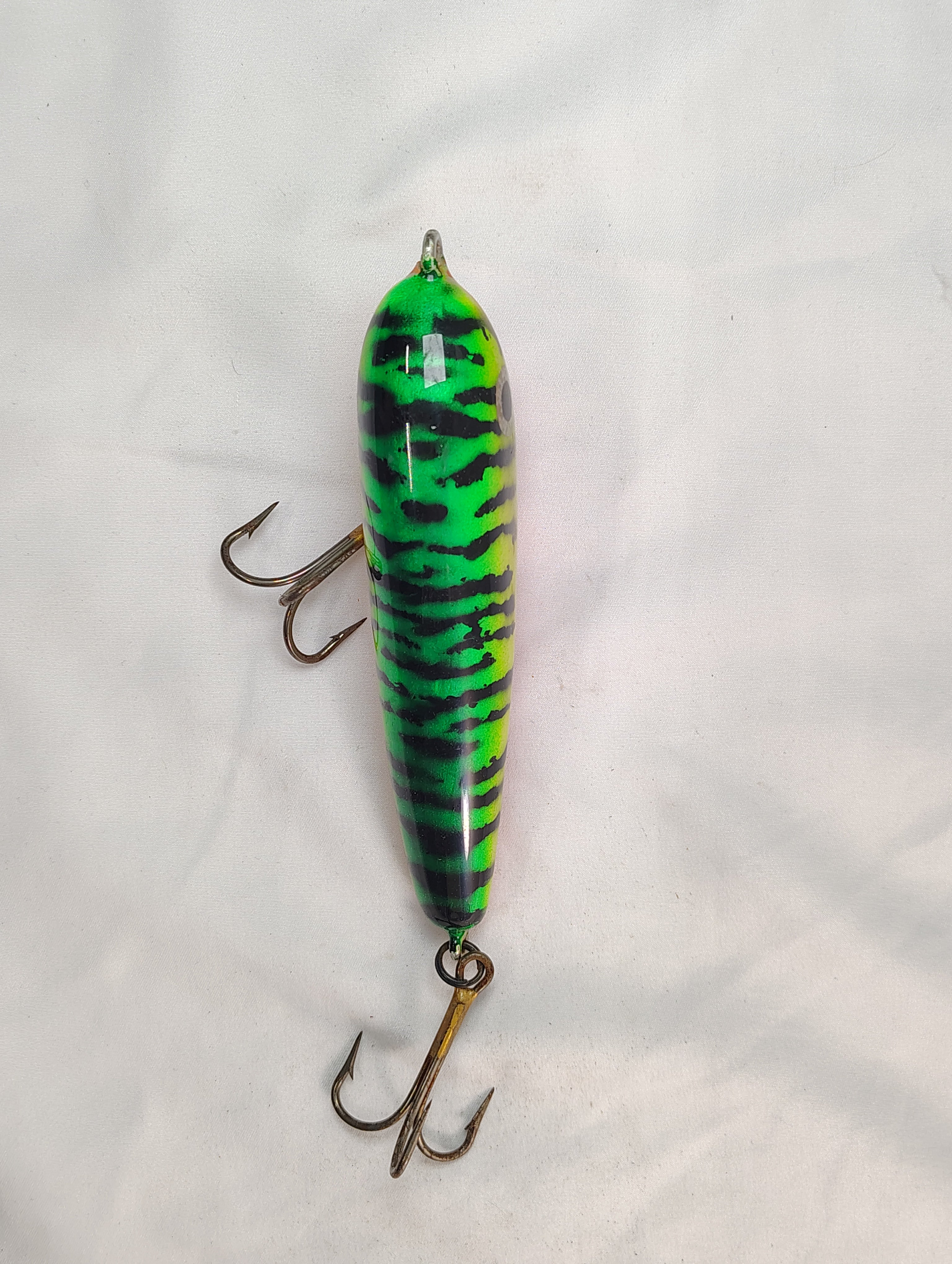 Green and black striped fishing lure on a white background