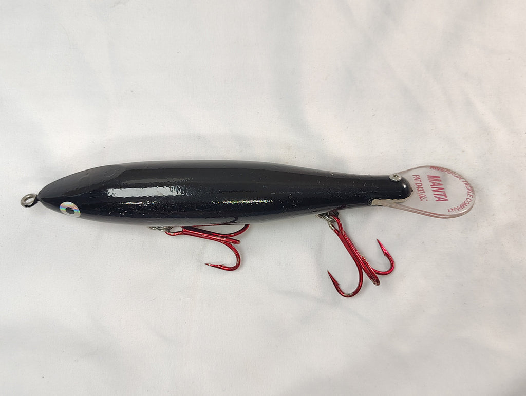 Black fishing lure with red hooks on a white background