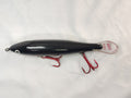 Black fishing lure with red hooks on a white background