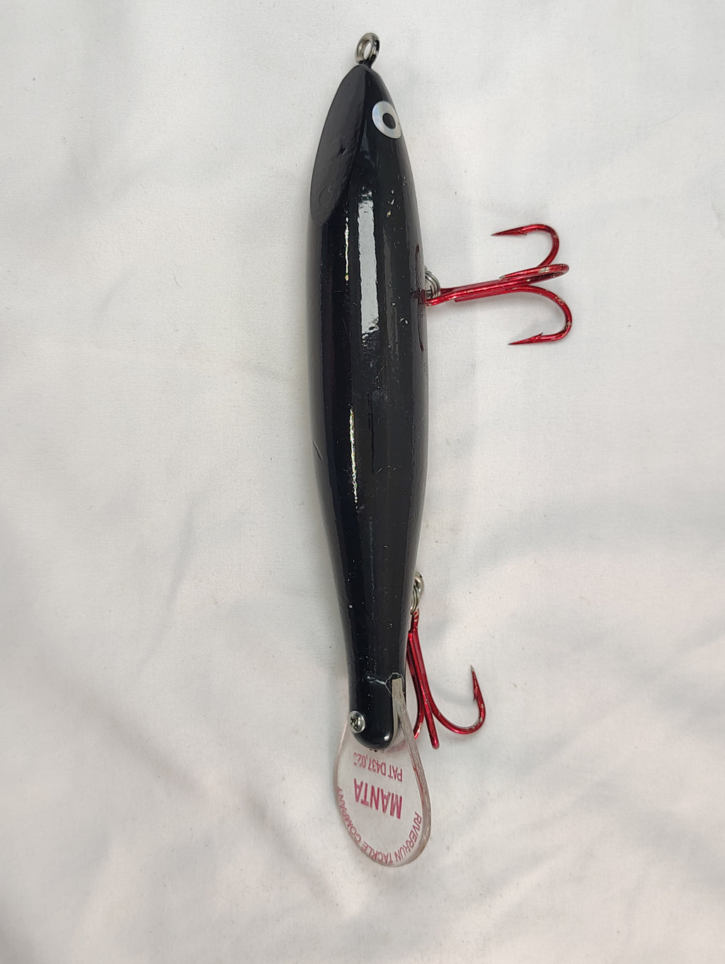 Black fishing lure with red hooks on a white background