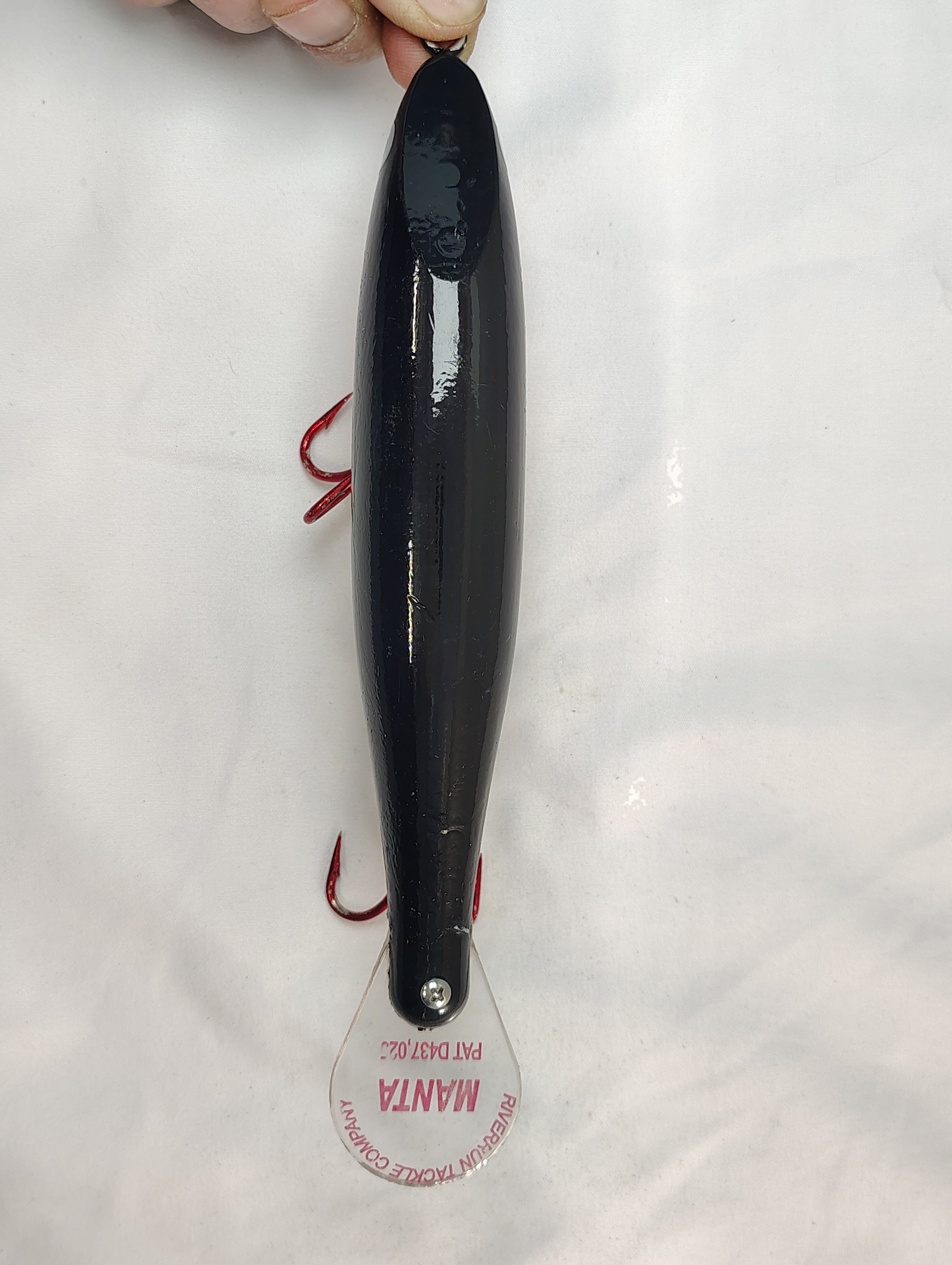 Black fishing lure with a visible brand label on a white background