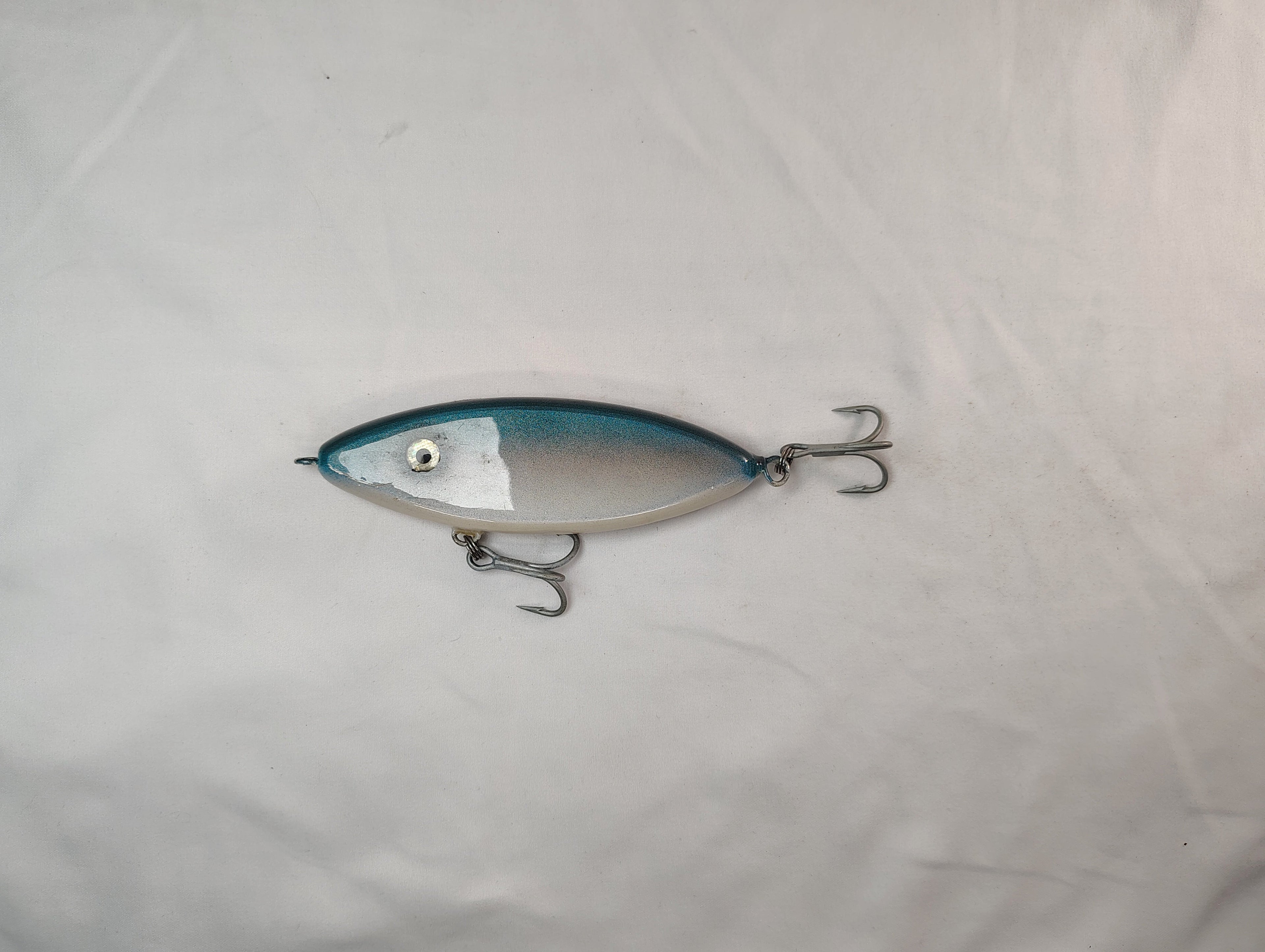 Fishing lure with a metallic finish on a white background