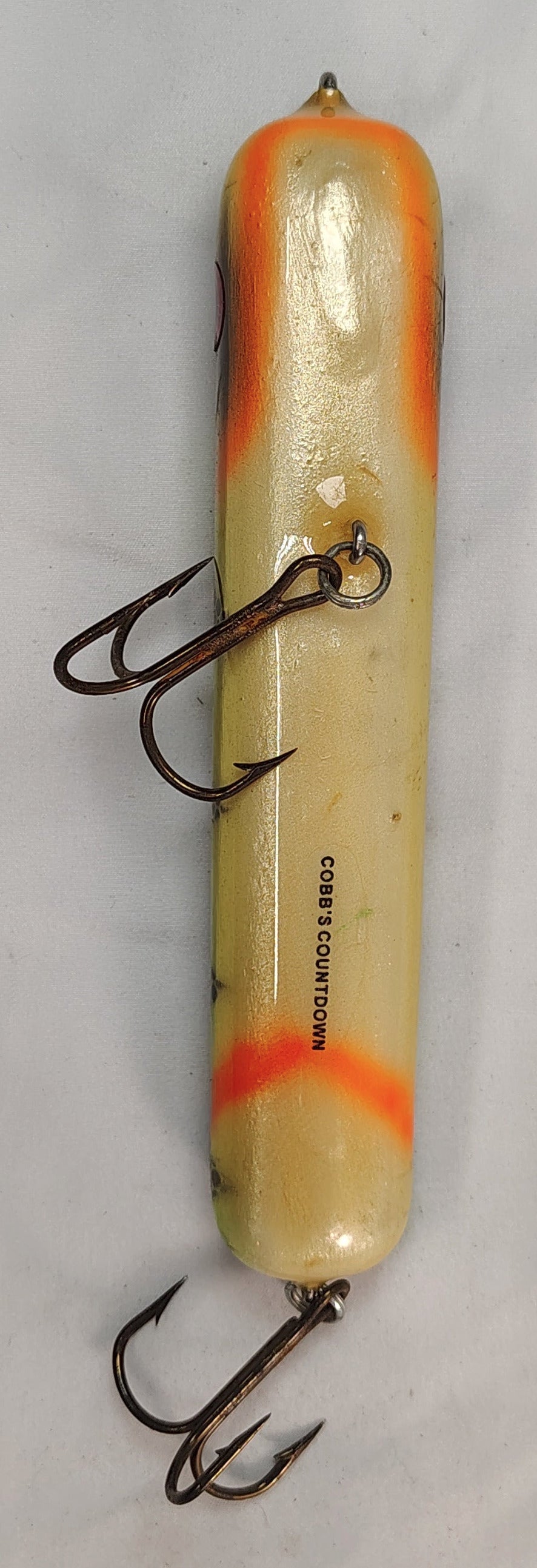 Fishing lure with a white body and orange stripe on a gray background