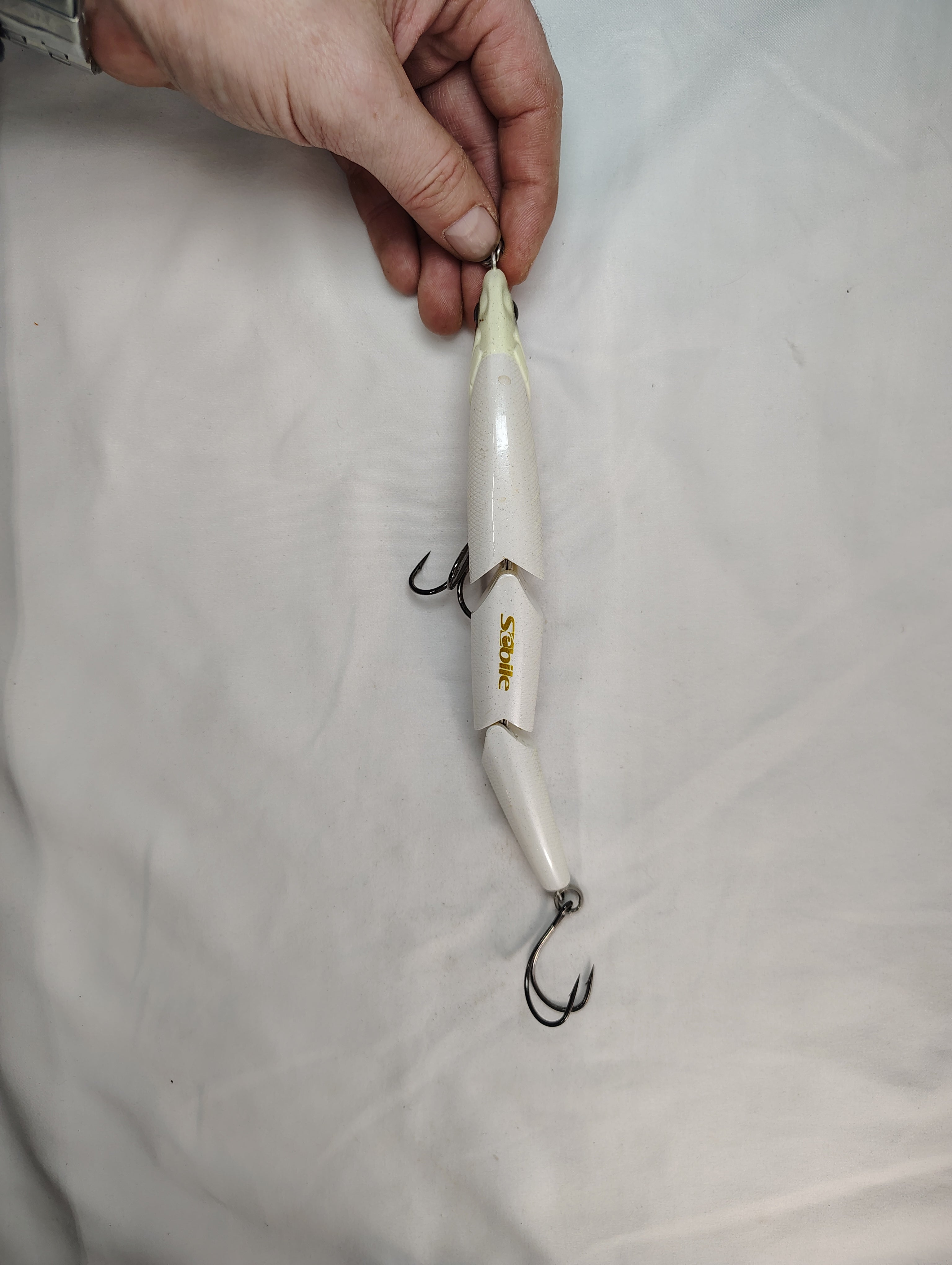 Fishing lure held by a hand on a white background
