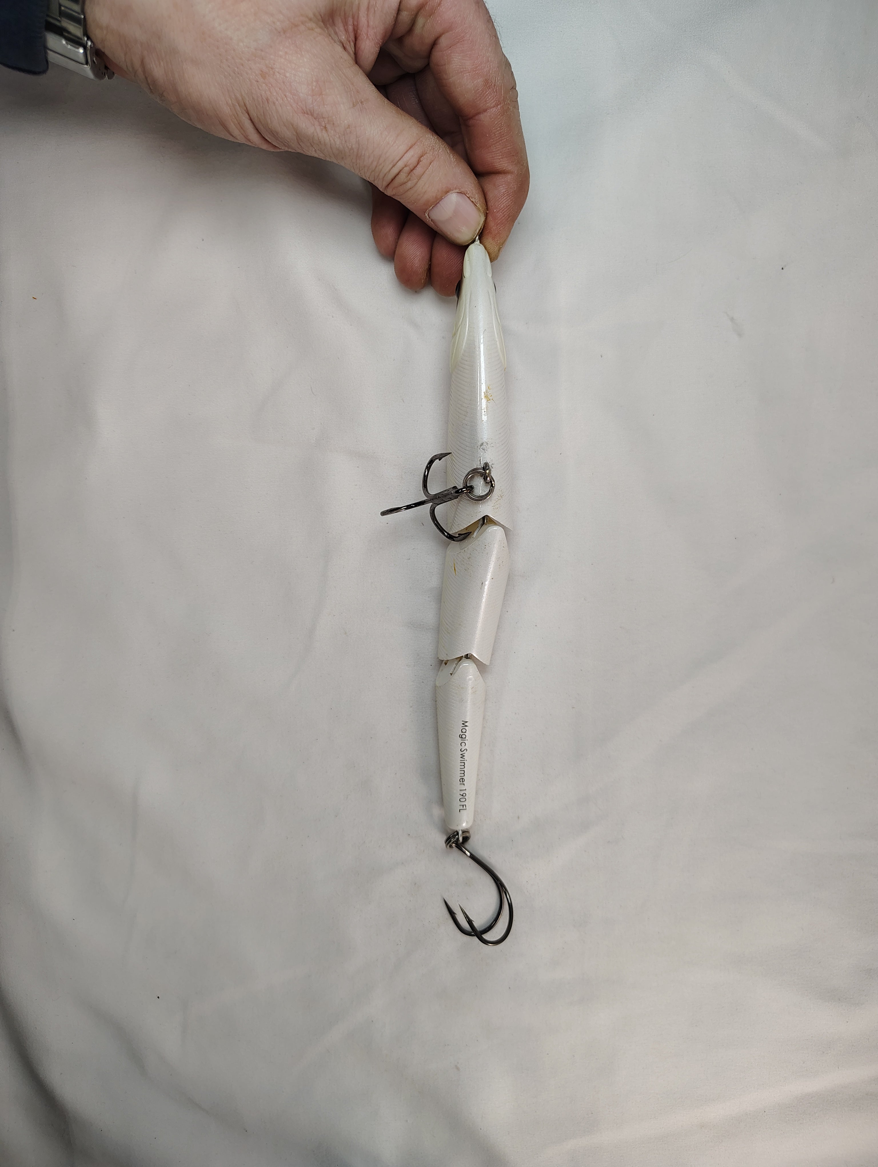 Fishing lure held by a hand on a white background