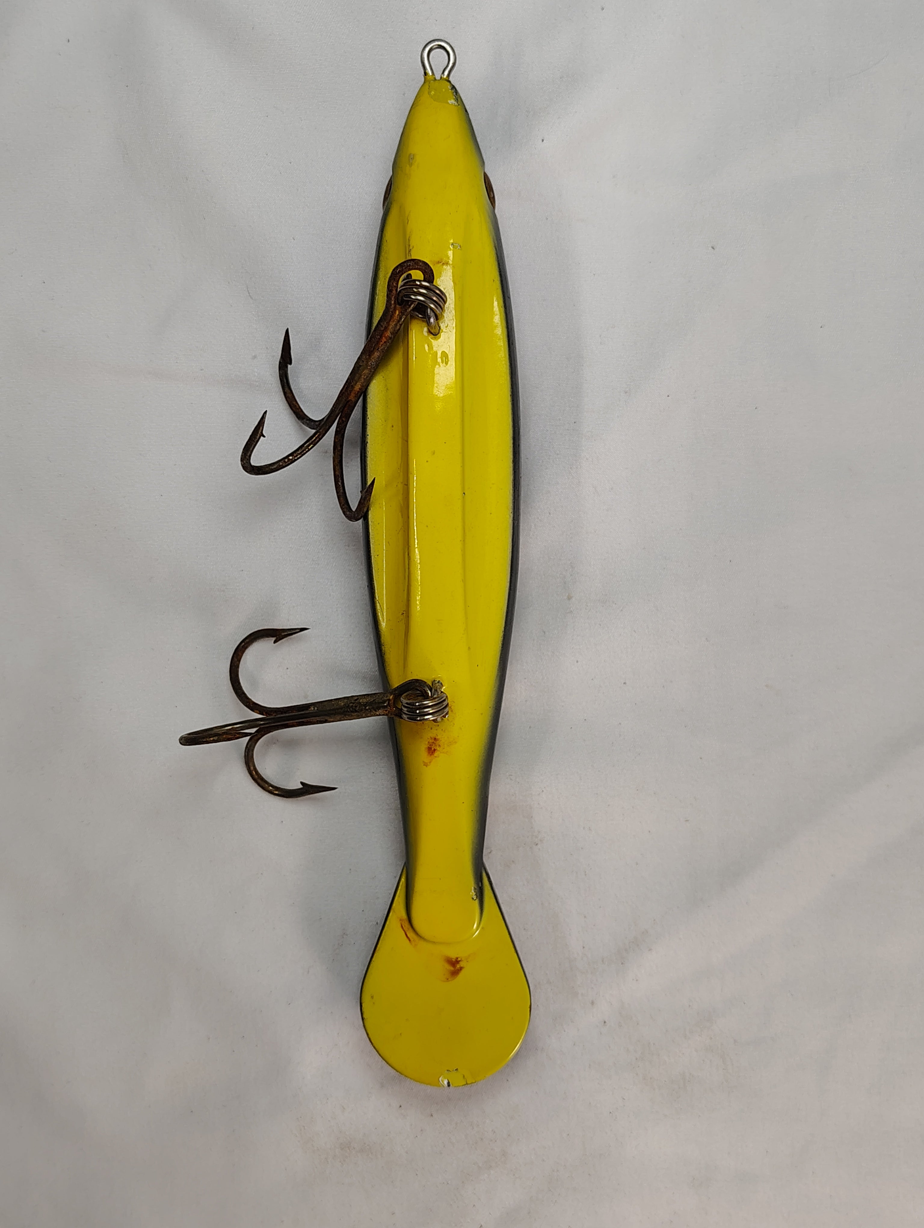Yellow fishing lure with treble hooks on a white background