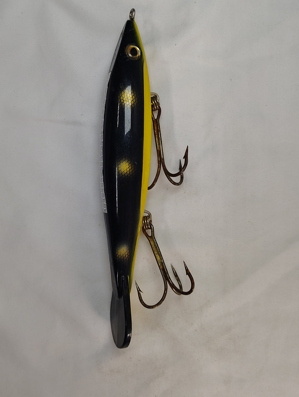 Yellow and black fishing lure with treble hooks on a white background