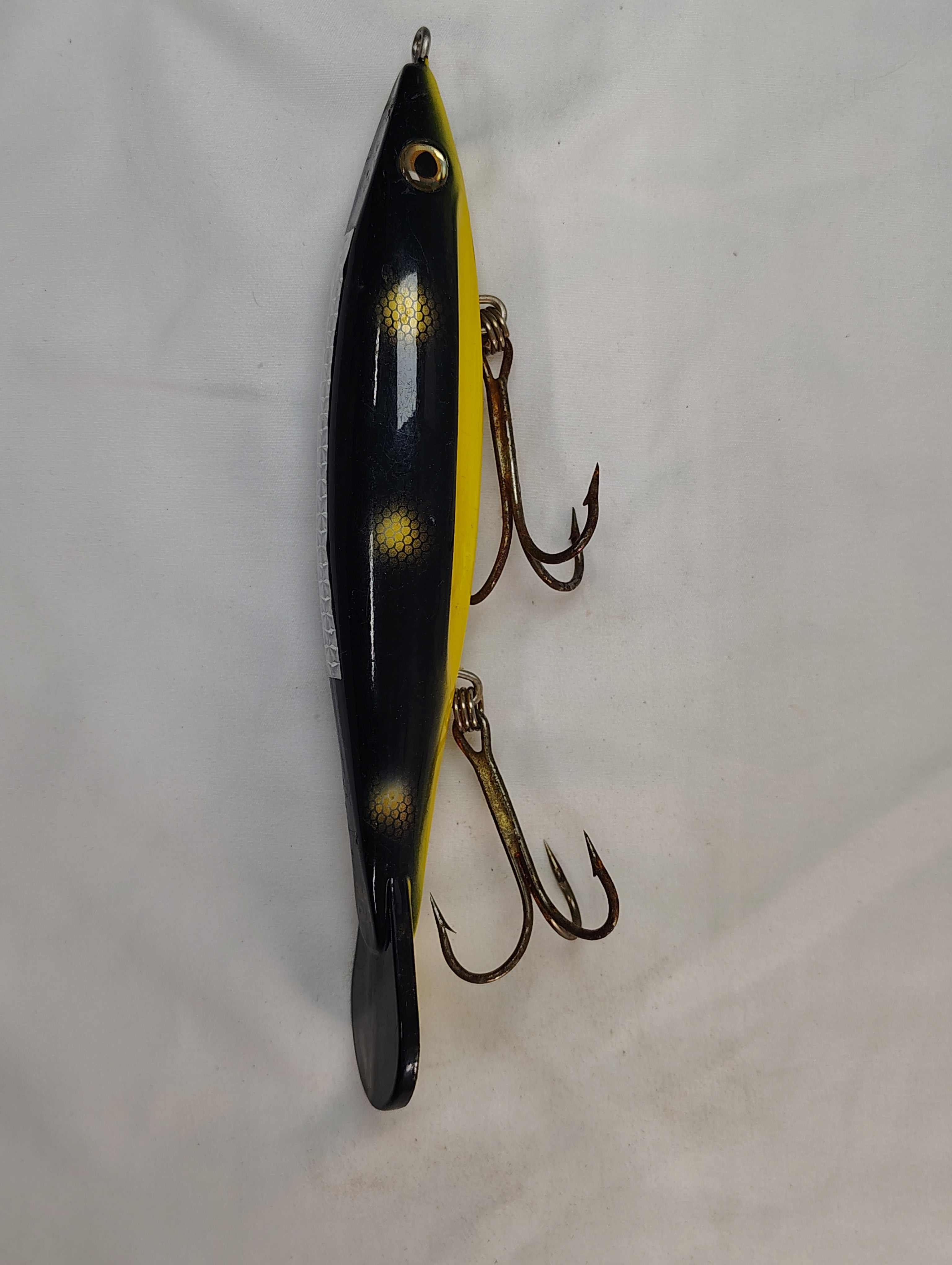 Yellow and black fishing lure with treble hooks on a white background