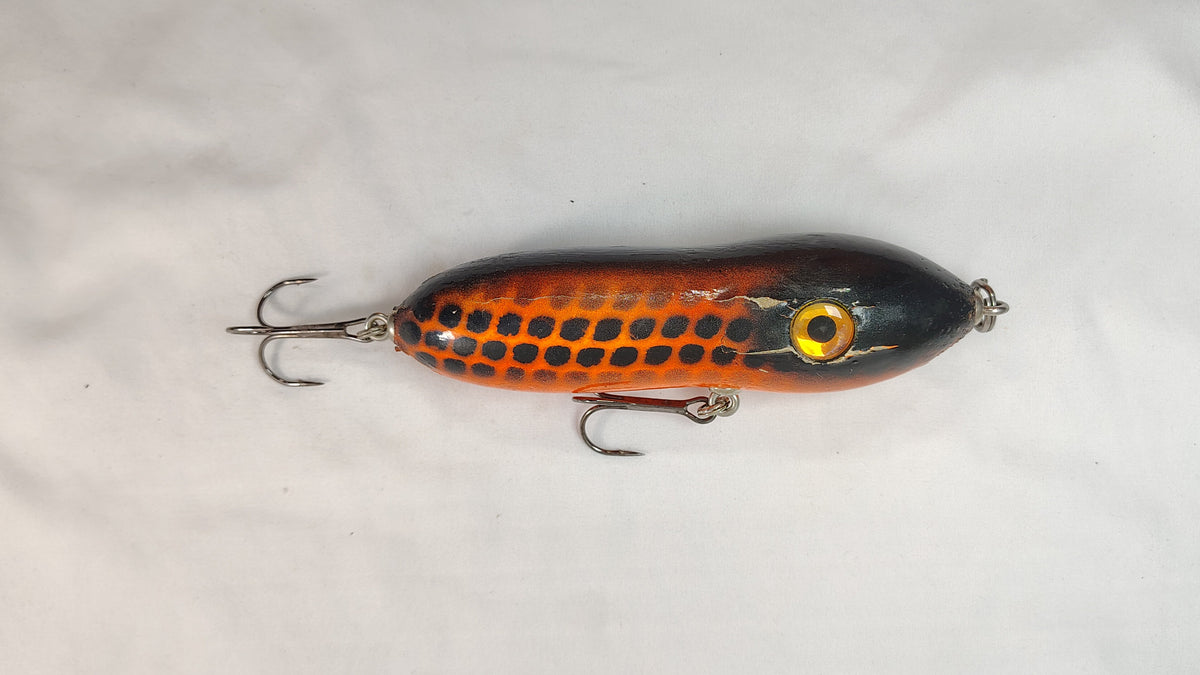 Fishing lure with black and orange pattern on a white background