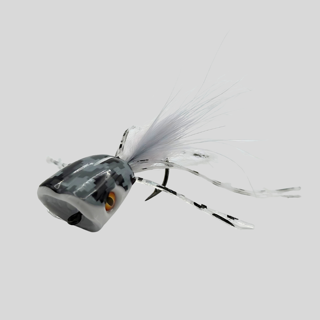 A fishing lure with a gray and black marbled head, a realistic orange eye, and white feathered tails on a light gray background.